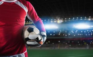 Goalkeeper holds the ball in the stadium during a football game photo