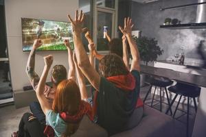 Group of friends watch the game together on television and rejoice photo