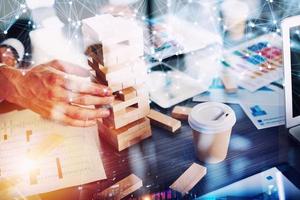 Business people build a tower of wooden bricks in the office. Concept of teamwork and partnership. double exposure with light effects photo