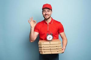 Courier is punctual to deliver quickly pizzas. Cyan background. photo