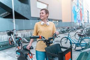 mujer toma un alquilado bicicleta en un bicicleta estacionamiento foto