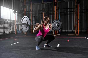 atlético niña trabajos fuera a el gimnasio con un barra con pesas foto