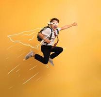 Young boy student jumps high like a super hero. Yellow background photo