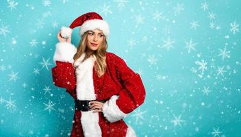 Blonde girl with Santa Claus costume on cyan background photo