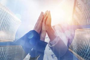 Three business people hit high five outside the office. Double exposure with light effect photo