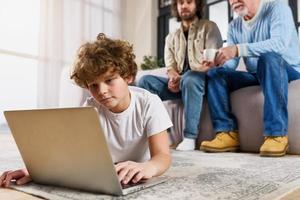 Children surfs on the web with a laptop at home with his family photo