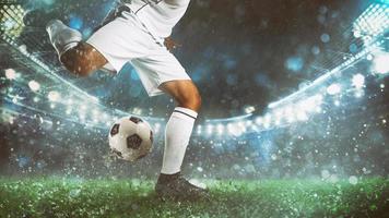 Close up of a soccer scene at night match with player in a white uniform kicking the ball with power photo