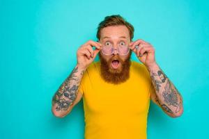Man with yellow t-shirt and beard is shocked about something photo