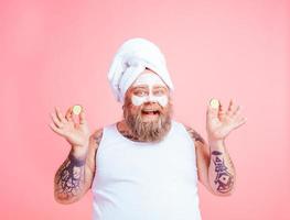 Man with beard acts like a woman and has fun with a facial mask photo