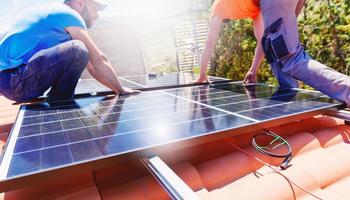 Workers assemble energy system with solar panel for electricity and hot water photo