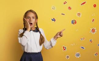 Young student is with shocked expression and indicates covid-19 bacteria. Yellow background. photo