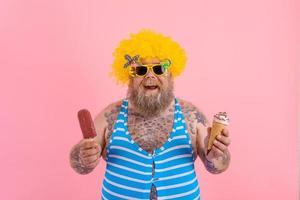 Fat man with beard and wig eats a popsicle and an icecream photo