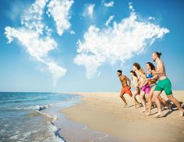 Group of friends run in the sea with world map made of clouds. Concept of summertime photo