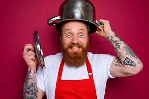 Happy chef with beard and red apron plays with pot photo