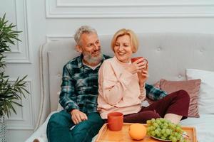 husband and wife have breakfast on the bed with coffee and fruit photo