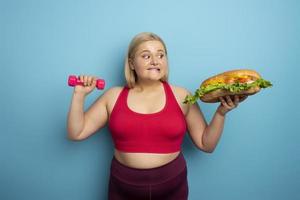 Fat woman does gym and want to eat a sandwich. Concept of food temptation photo