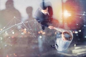 Handshaking business person in office with network effect. concept of teamwork and partnership. double exposure photo