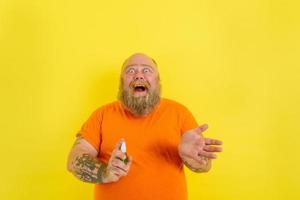 Happy man with beard and tattoos holds a hands cleaner against covid19 photo