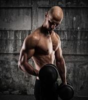 Athletic man training biceps on grunge background photo