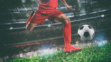 Close up of a soccer scene at night match with player in a red uniform kicking the ball with power photo