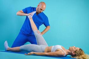 Girl performs exercises with a physiotherapist. Cyan background photo