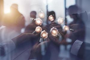 Teamwork and brainstorming concept with businessmen that share an idea with a lamp. Concept of startup. Double exposure photo