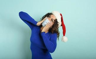 Woman with face mask is wondered about something. cyan background photo