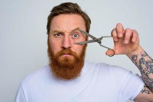 Serious man with scissors is ready to cut the beard photo