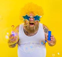 Amazed man with yellow wig in head play with bubbles soap photo