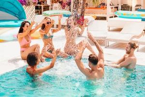 grupo de amigos en traje de baño disfrutar en un nadando piscina foto