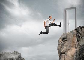 Businessman jumping over the mountains to reach a door photo