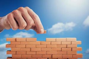 Businessman puts a brick to build a wall. Concept of new business, partnership, integration and startup photo