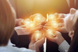 Teamwork and brainstorming concept with businessmen that share an idea with a lamp. Concept of startup photo