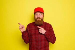 Happy delivery man with hat and beard indicates something photo