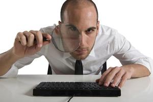 Businessman looks on the computer with a lens photo