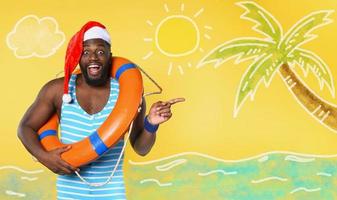 Black man in swimsuit ready to go in a sunny place for christmas. Yellow background photo
