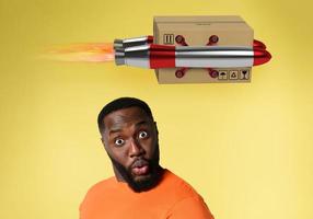 Black man with surprised and amazed expression. concept of express and priority shipment. yellow background photo