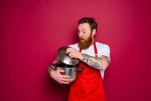 sorprendido cocinero con barba y rojo delantal es Listo a cocinar foto