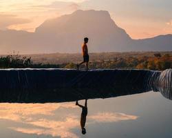 A man walking on reservoir with mountain peak reflection in countryside photo