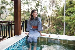 Young asian woman in bathrobe sitting on natural hot spring pool at the resort photo