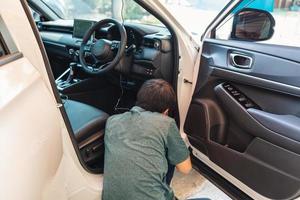 Mechanic man checking and installing dash cam device with wire inside a car at garage photo