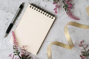 Beautiful  flower and notebook on marble background photo