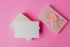 white paper and gift box on pink background decorated with flowers photo