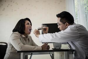 doctor in white uniform gown checkup patient's mouth with flashlight photo