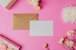 brown envelope and card with gift box on pink background decorated with flowers photo