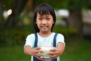 Little girl drinking milk in the park photo