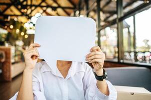 foto un joven mujer en un blanco camisa participación un pensamiento caja símbolo