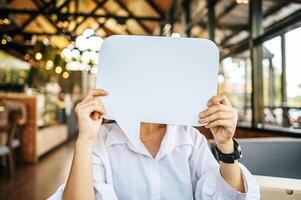 foto un joven mujer en un blanco camisa participación un pensamiento caja símbolo