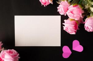 papel blanco y flores rosas pegadas sobre un fondo negro foto