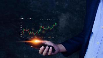 Businessman touching points smartphone with checking trend chart growing up, symbol stock graph and chart background, concept growth and development business investment photo